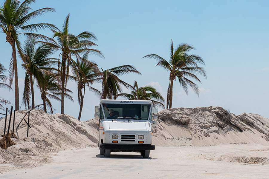 Postal delivery vehicle drives along sand dunes