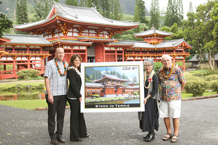 People hold stamp artwork in front of temple