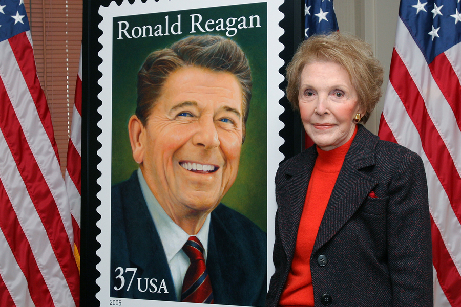 Nancy Reagan stands next to Ronald Reagan stamp artwork