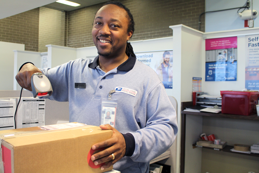 Smiling postal worker scans package