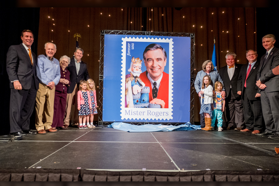 Large group stands near Mister Rogers stamp poster