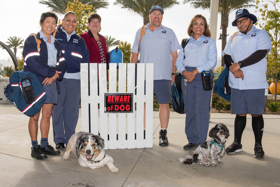 Postal workers smile and pose with two dogs