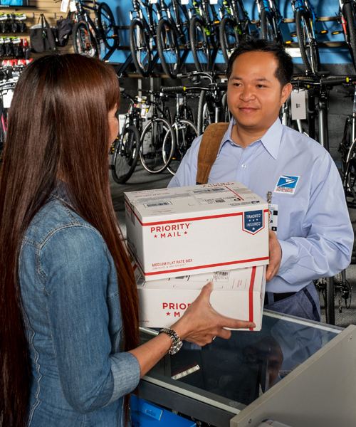 Letter carrier picks up packages at bike shop