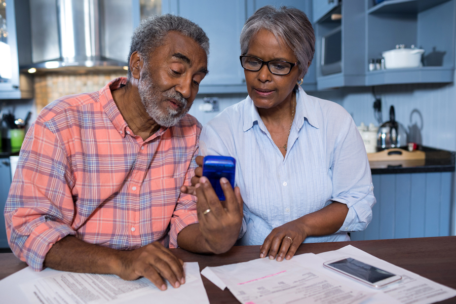 Older couple sit at kitchen table and look at calculator