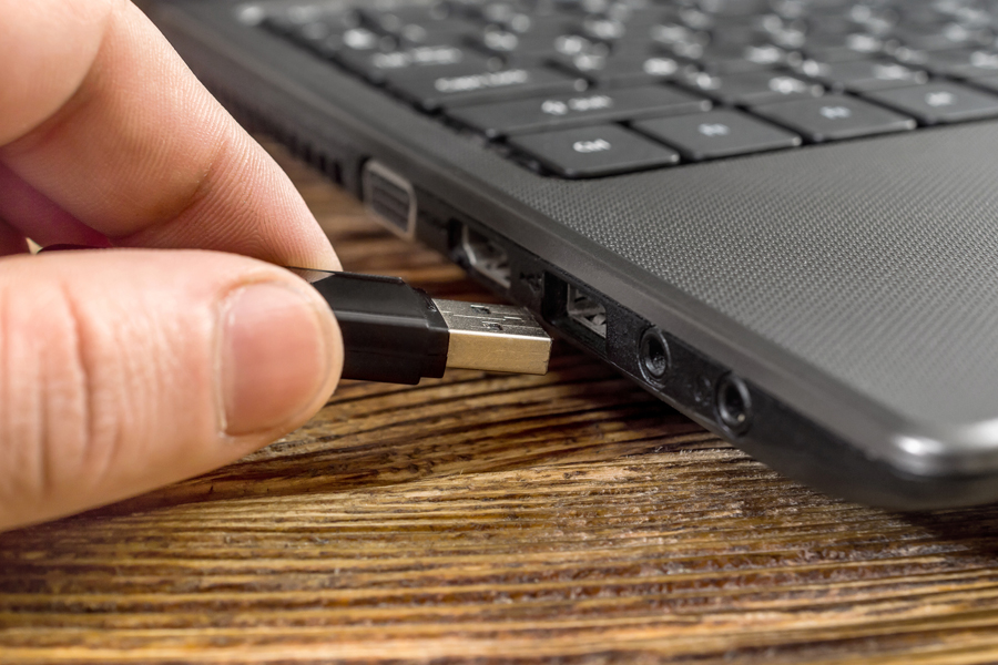 Fingers plug cord into laptop port