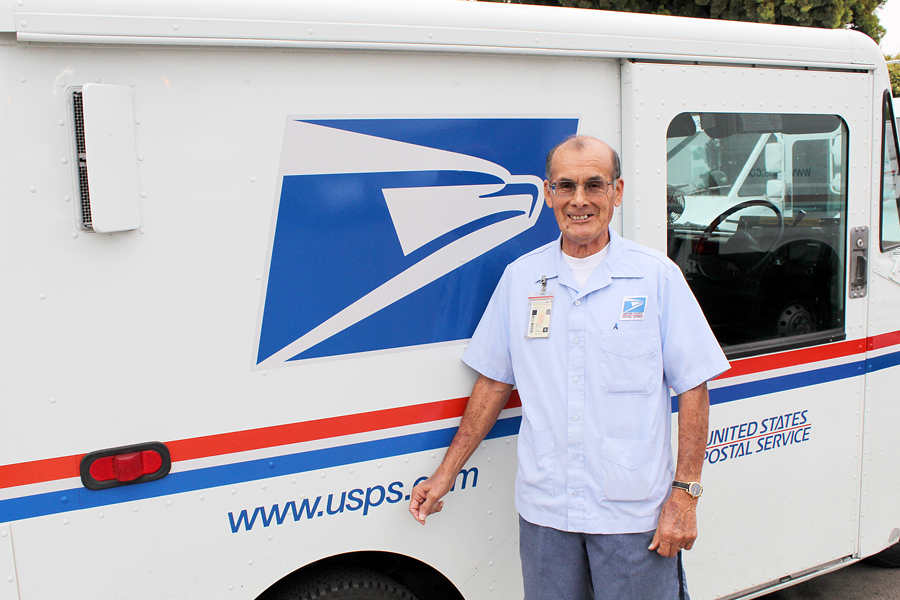 Postal worker stands next to delivery vehicle