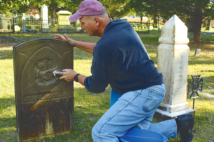 Kneeling man scrubs headstone