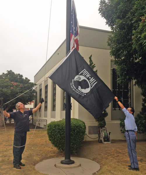 Two employees raise the POW-MIA flag