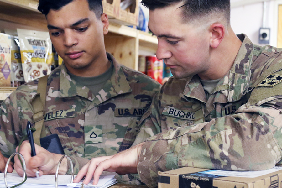Two Army soldiers sign for package at counter