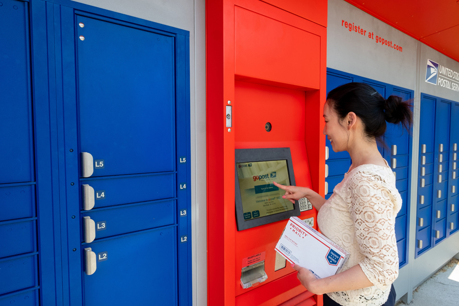 Woman presses keypad near bank of colorful parcel lockers