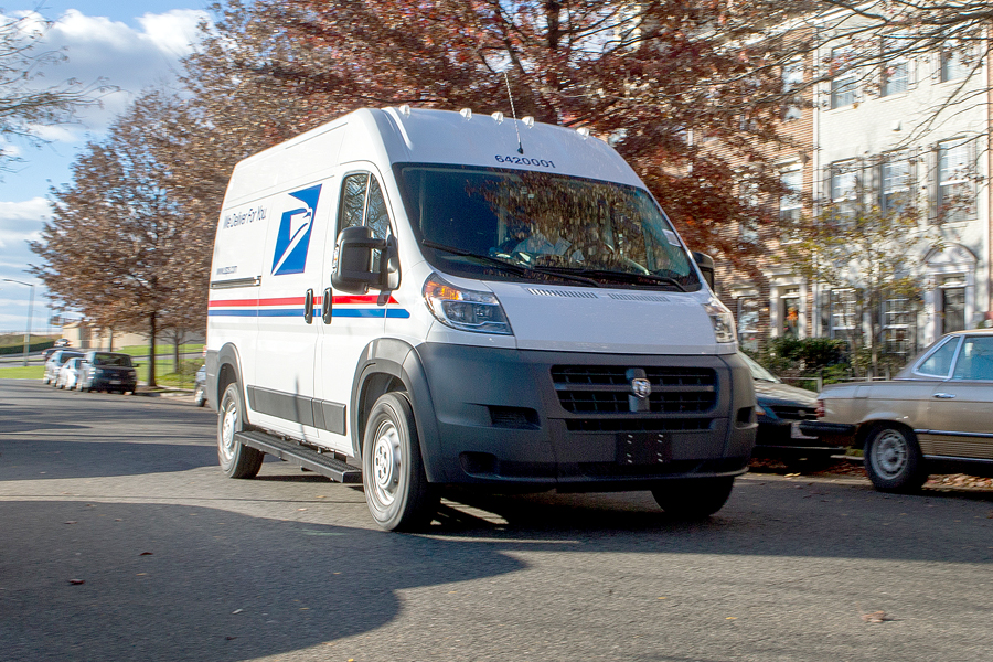 USPS delivery vehicle moves along neighborhood street