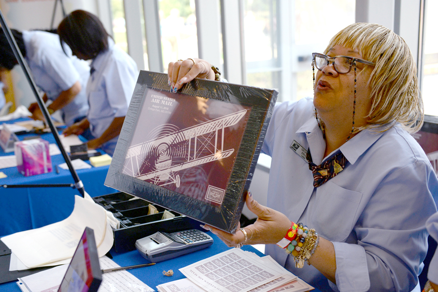 Postal worker hands framed artwork to customer