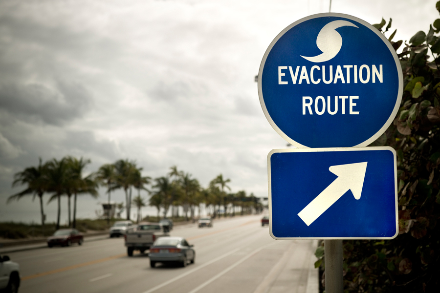 Vehicles drive past Evacuation Route signage on highway