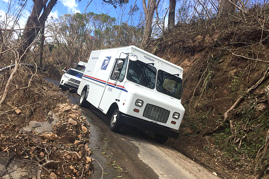 USPS delivery vehicle travels along washed out rural road