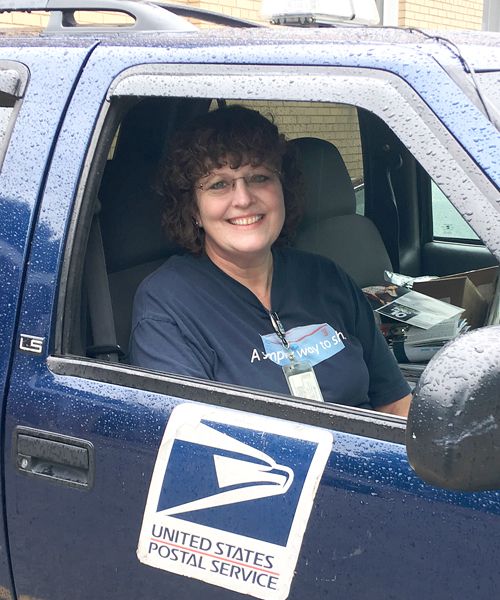 Smiling woman sits inside USPS-branded vehicle