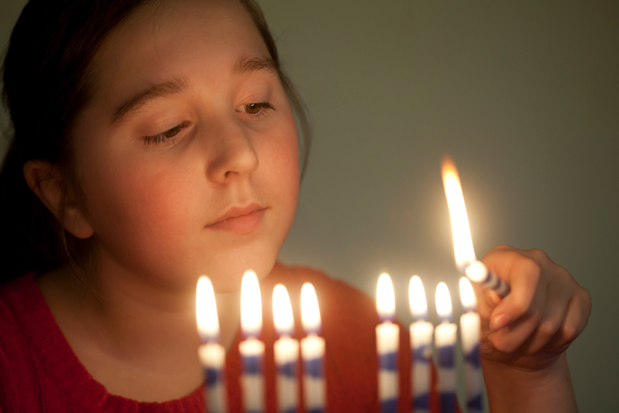 Girl lighting menorah
