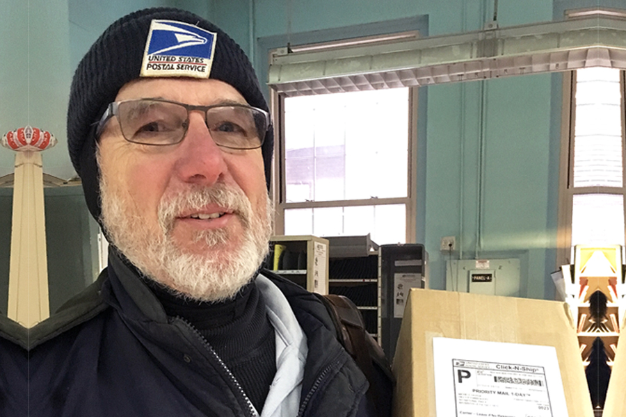 Letter carrier stands in postal work room