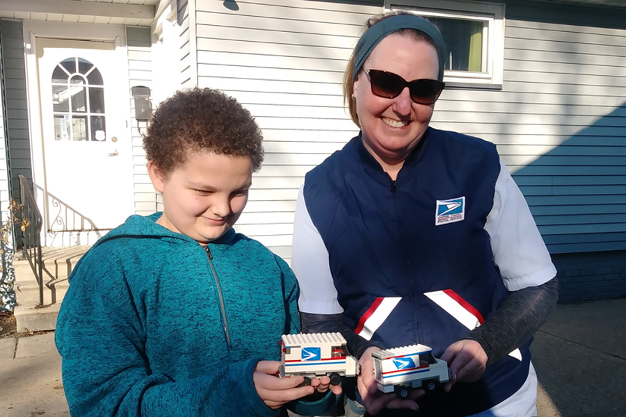 Letter carrier and boy with Lego replica of postal vehicle