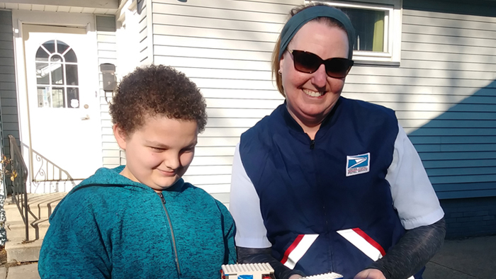 Letter carrier and boy with Lego replica of postal vehicle