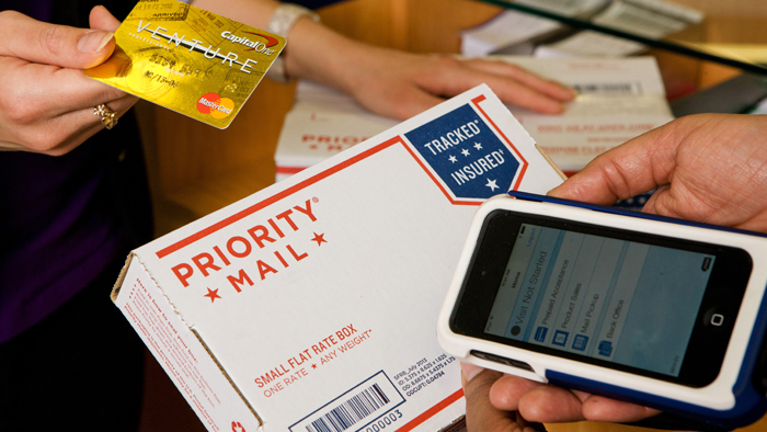Postal employee scanning bar code of a Priority Mail package
