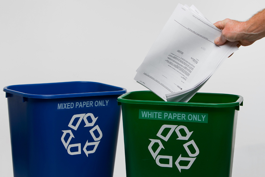 Hand places paper in recycling bin