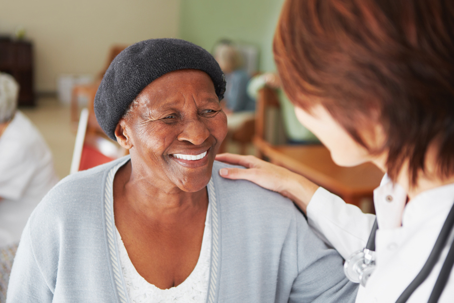 Nurse places hand on shoulder of smiling elderly woman