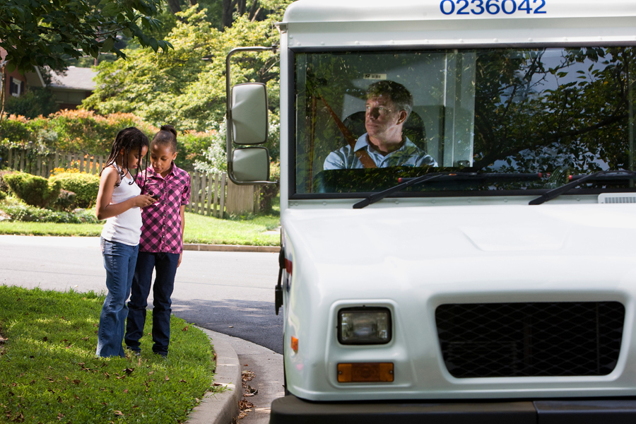Children standing near a postal truck