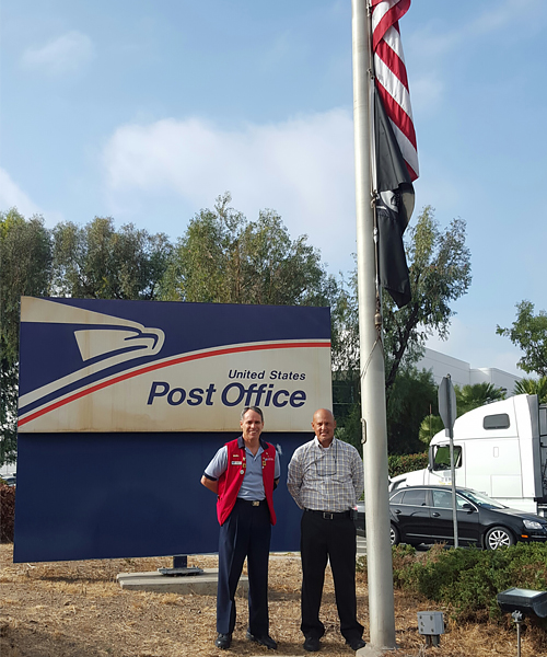 Two men standing by a flag pole.