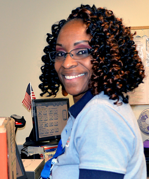 Smiling postal worker stands at Post Office retail counter