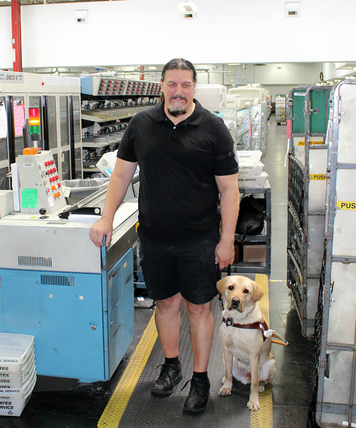 Postal employee with his service dog at postal plant.