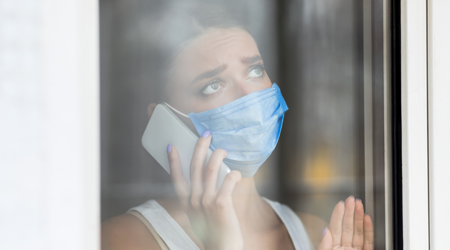 Woman wearing face mask talks on a phone.