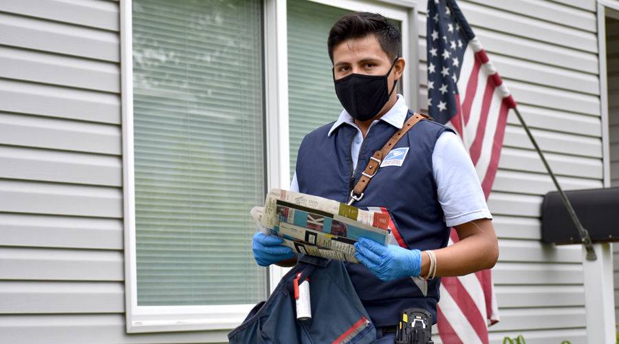 Masked letter carrier stands near home