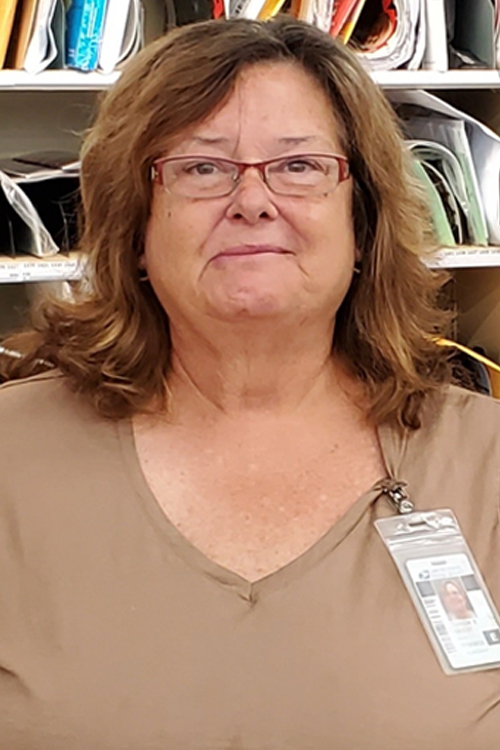 Smiling woman stands in Post Office workroom
