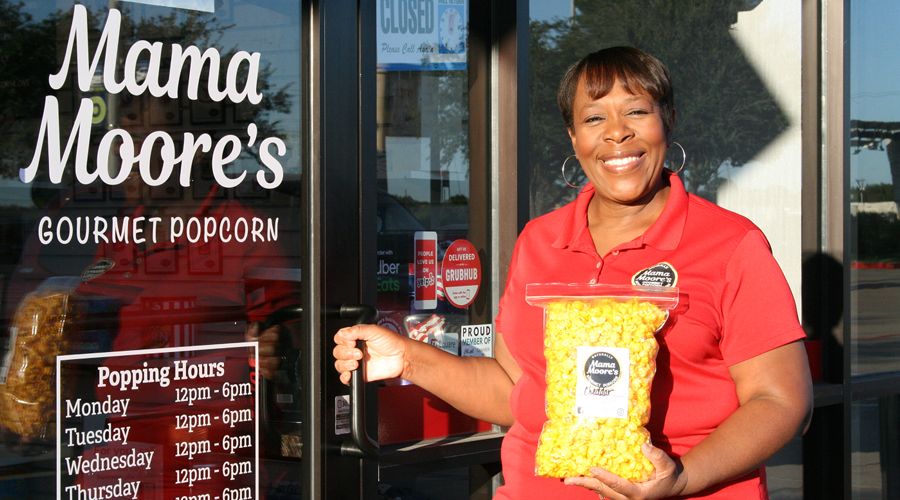 Smiling woman stands outside popcorn company storefront