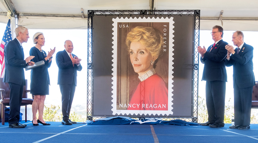 People applaud as drape falls, unveiling stamp image