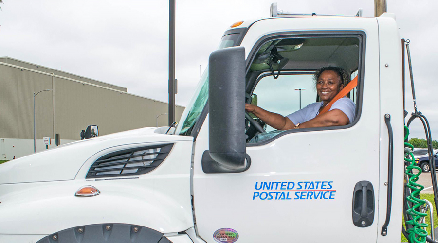 Smiling woman sits in driver's seat of big rig truck